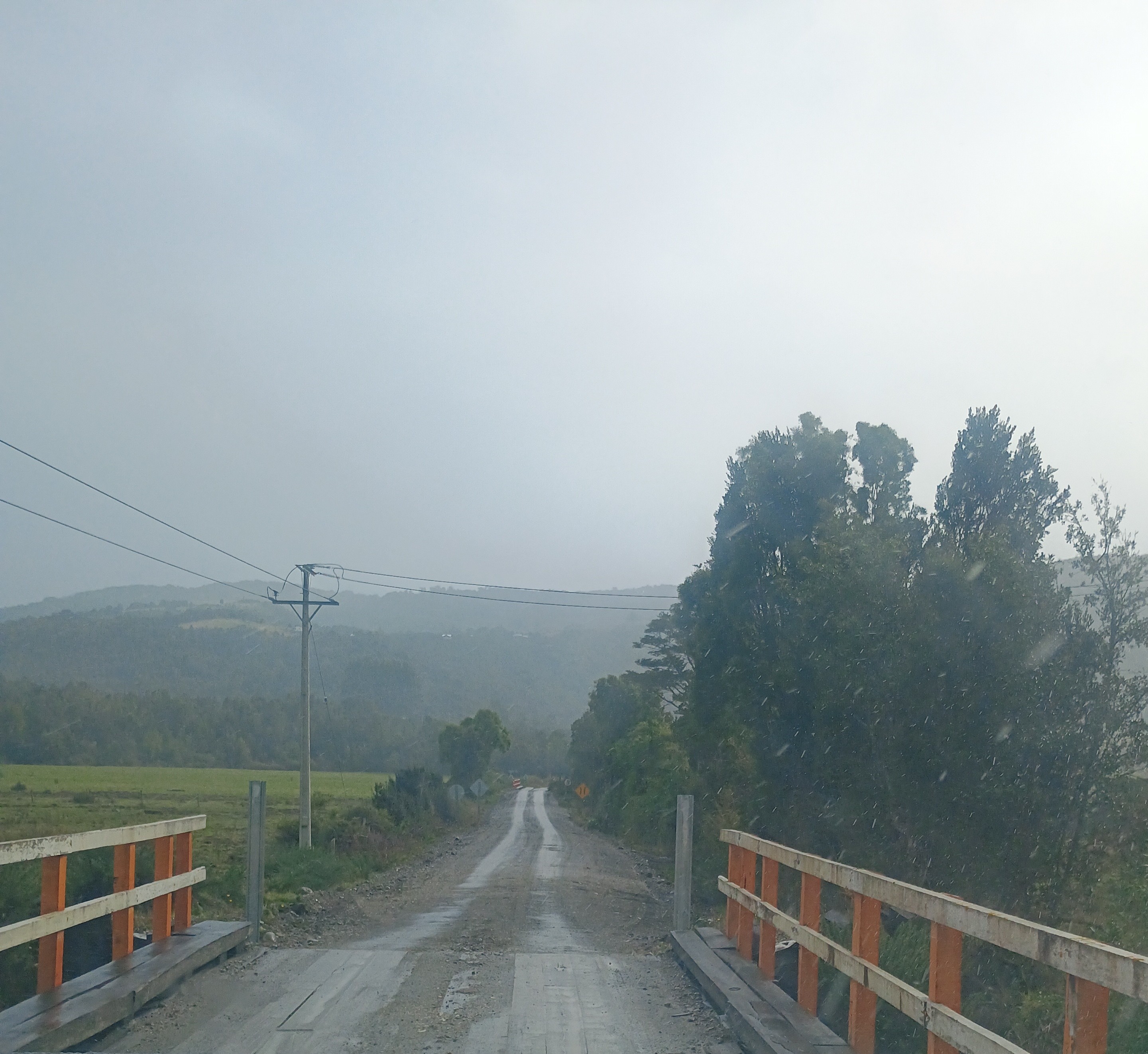 Puente rural con camino de ripio y colinas verdes